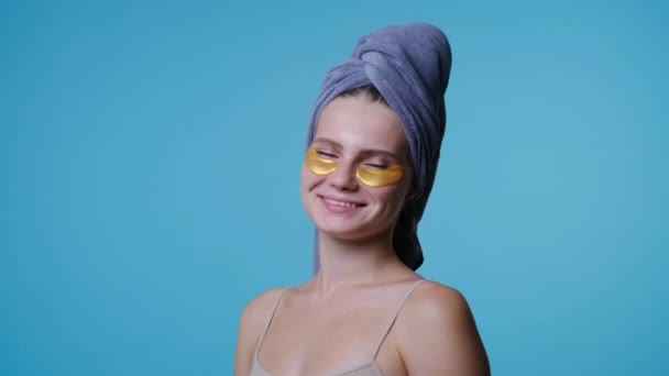 Дівчина в рушнику на голові з плямами очей дивиться на камеру — стокове відео