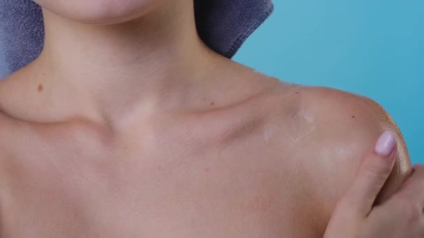 Молодая женщина наносит лосьон на плечо, используя крем — стоковое видео