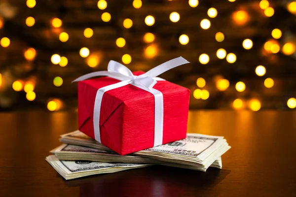 背景にぼやけたライト上の米国100ドル札の赤いギフトボックス 米ドルだ クリスマスと新年のお金が存在します 贈り物代だ １００ 金融とビジネスの概念 クリスマスショッピング ストック写真