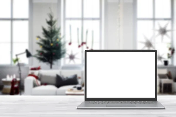 白い木製のテーブルの上に空白の画面のラップトップコンピュータ クリスマスの装飾が施されたモダンな居心地の良い家庭のリビングルーム ホームオフィスのデスクワークスペース コピースペースをモックアップします 冬の販売 オンラインショッピング ロイヤリティフリーのストック写真