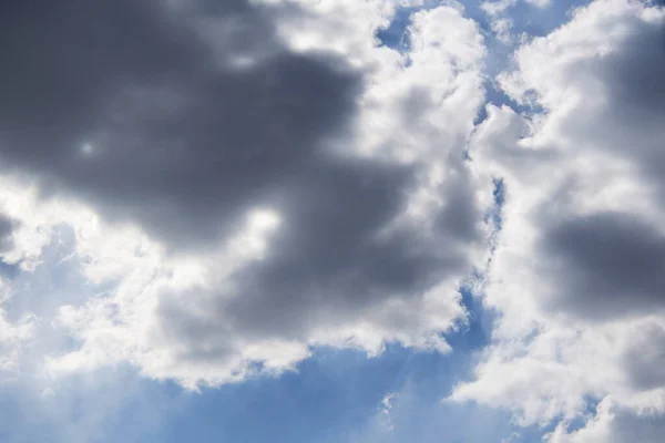 Güneş mavi gökyüzündeki kara bulutların arasından yol açar.