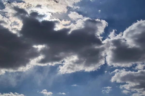 Güneş mavi gökyüzündeki kara bulutların arasından yol açar.