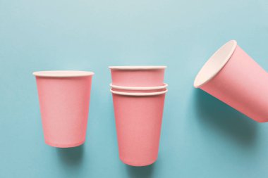 Açık mavi arkaplanda izole edilmiş pembe kağıt bardakların yakın çekimi
