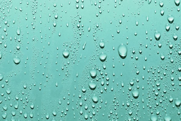 Close up of water drops on smooth surface, blue background