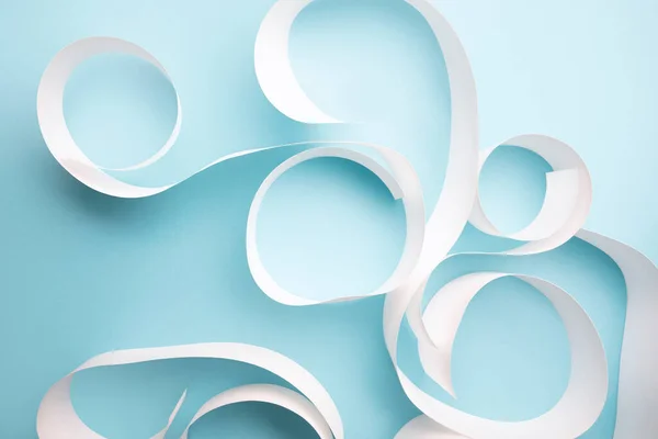 Açık mavi arkaplanda beyaz kağıt kıvrımlarının yakın plan görüntüsü