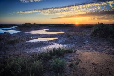 Gün batımında sığ bir bataklık, gökte bulutlar