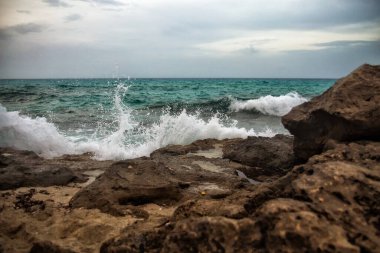 Dalgalar kayalara çarpıyor ve sıçrıyor.