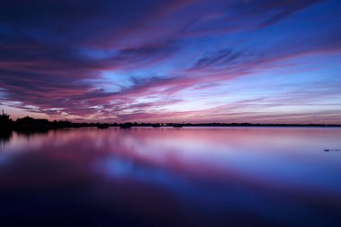 Alacakaranlıkta bir gölden yansıyan bulutlar