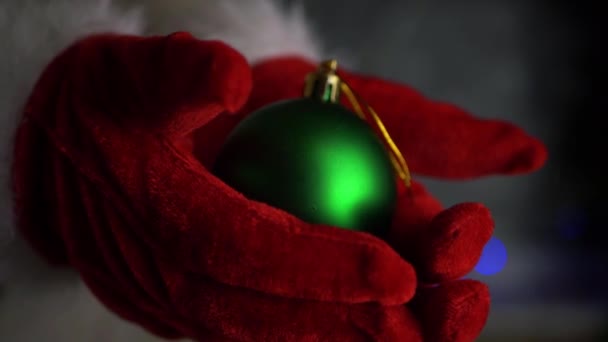 Hands wearing Santa gloves holding green bauble — Stock Video