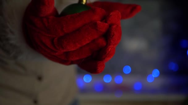 Hände mit Nikolaushandschuhen halten grüne Christbaumkugel — Stockvideo