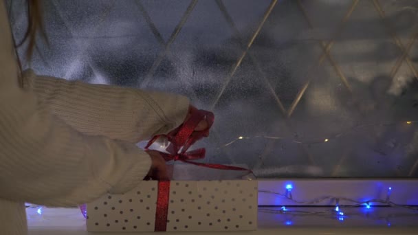 Frau öffnet Geschenk in Weihnachtsfenster-Szene — Stockvideo