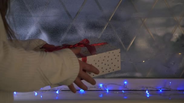 Vrouw met een geschenk in kerst venster scene — Stockvideo