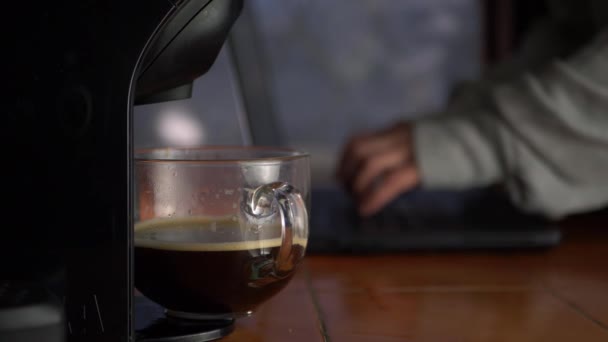 Fresh coffee jug with woman working on laptop in background — Stock Video