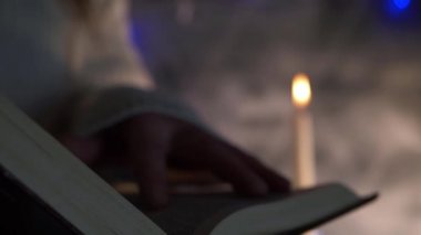 Mum ışığında pencerede kitap okuyan eller 