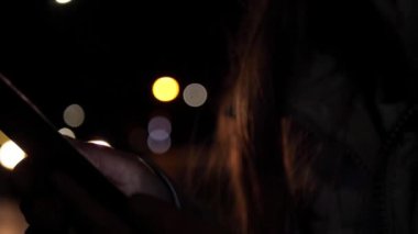 Akşamları trafik arkaplanı olan akıllı telefon kullanan eller