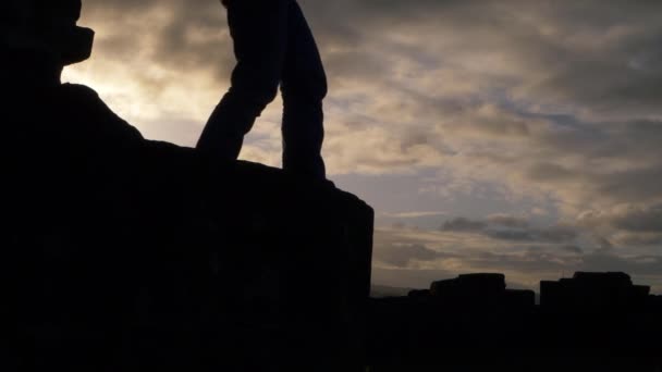Kobieta wspinająca się na skały przed chmurnym niebem — Wideo stockowe