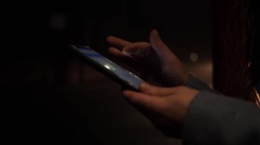 Gece akıllı telefon kullanan bir kadın. Trafik arkaplanı var.