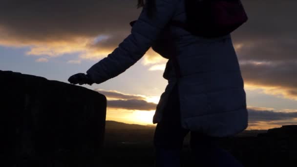 Mulher escalando pedras contra o pôr do sol — Vídeo de Stock