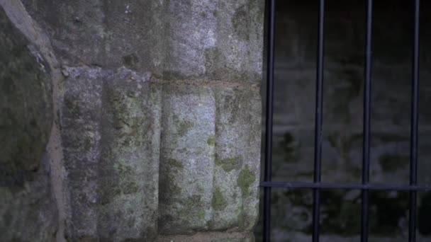 Metalen staven buiten stenen poort van oude stenen kerker — Stockvideo