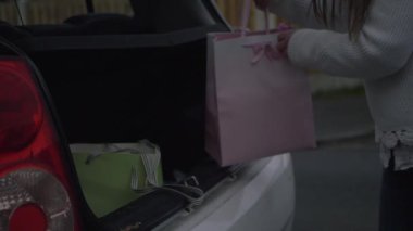Kadının biri araba bagajından alışveriş yapıyor.