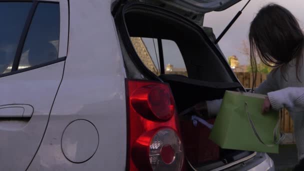 Femme mettre des sacs de shopping dans la botte de voiture — Video