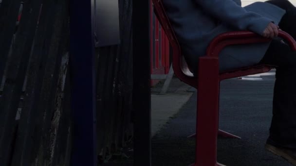妇女坐在空荡荡的火车站的长椅上 — 图库视频影像