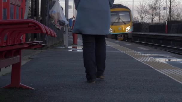 Mujer camina en la estación de tren vacía como tren sale — Vídeos de Stock