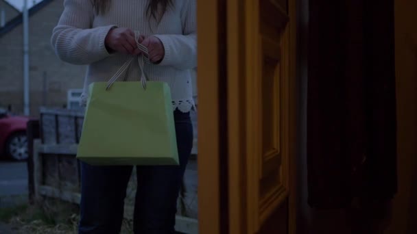 Mujer visita a casa y sostiene una bolsa de regalo — Vídeos de Stock