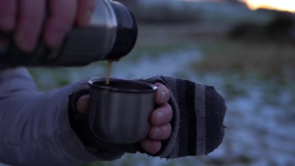 Руки в рукавицах наливая напиток из термос фляжки в зимний день — стоковое видео