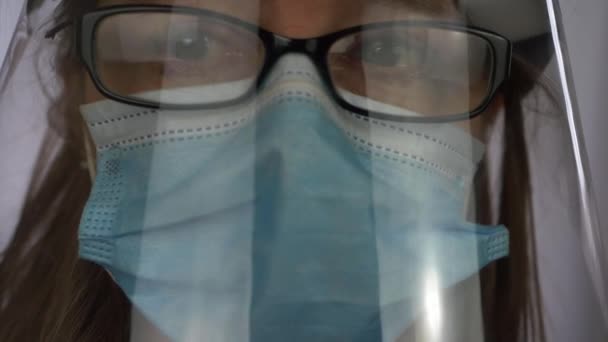 フェイスマスクとフェイスシールドを身に着けている女性医療スタッフは、カメラに見える — ストック動画