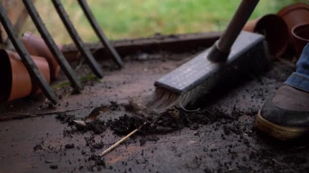 Gardener sweeping wooden hut covered in soil and dirt — Stock Video