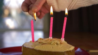 Doğum günü pastasında mum yakan eller.