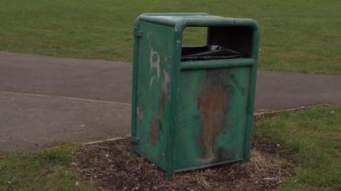 Bir şehir parkında eski püskü çöp kutusu