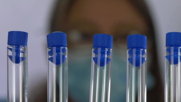 A equipe médica olha para a fileira de tubos de ensaio em um laboratório — Vídeo de Stock