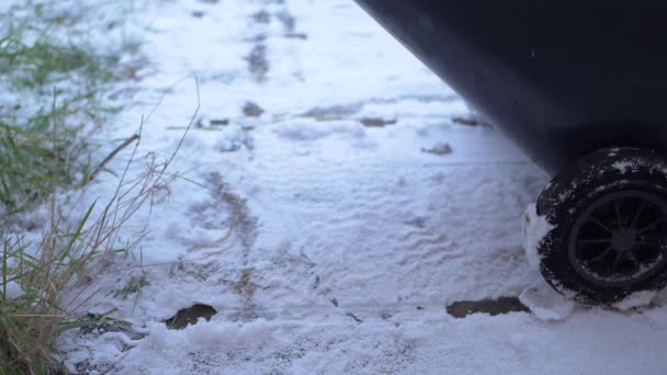 雪の中で車輪の上にゴミ箱を引く — ストック動画