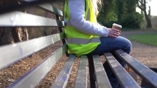 Kvinnlig arbetare tar kaffepaus på en parkbänk — Stockvideo