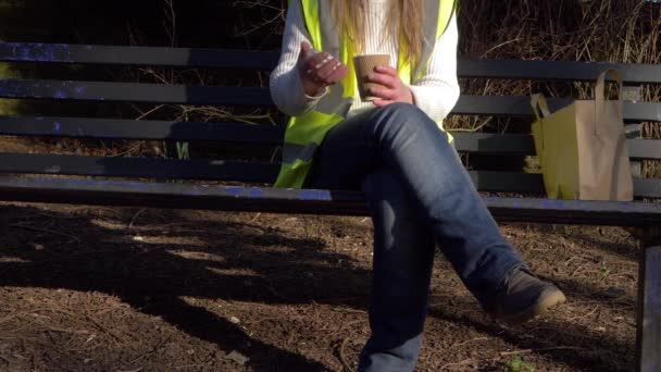 Kvinnlig arbetare tar kaffepaus på en parkbänk — Stockvideo