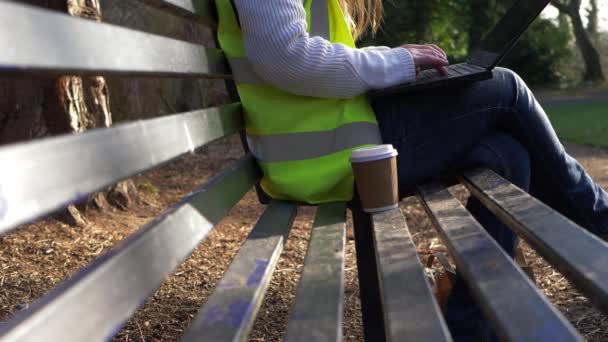 Wolontariusz konserwatorski pracujący na ławce w parku z laptopem — Wideo stockowe
