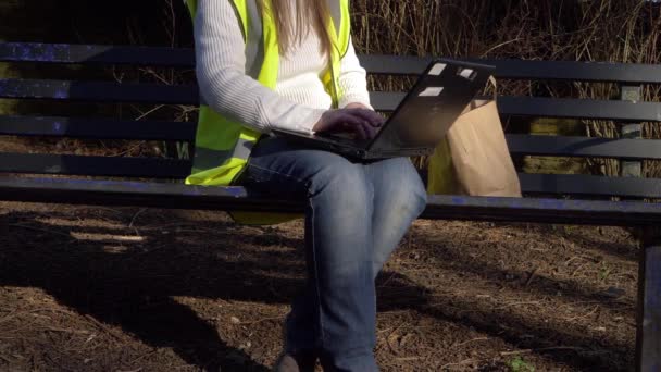 Εθελοντής συντήρησης που εργάζεται σε παγκάκι με laptop — Αρχείο Βίντεο