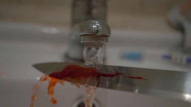 Suçlu lavabodaki keskin bıçakla kanı siliyor.