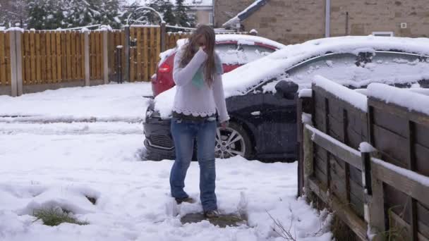 Vrouw loopt het tuinpad op als sneeuw valt — Stockvideo