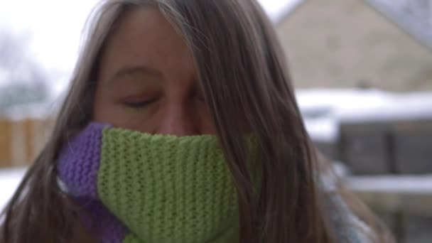 Жінка в зимовому шарфі посміхається в камеру в зимовій сцені — стокове відео