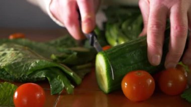 Mutfakta sağlıklı taze sebzelerle salatalık dilimliyorum.