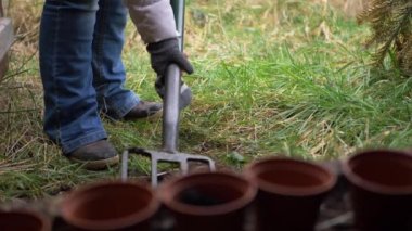 Gardener digging soil with row of plant pots
