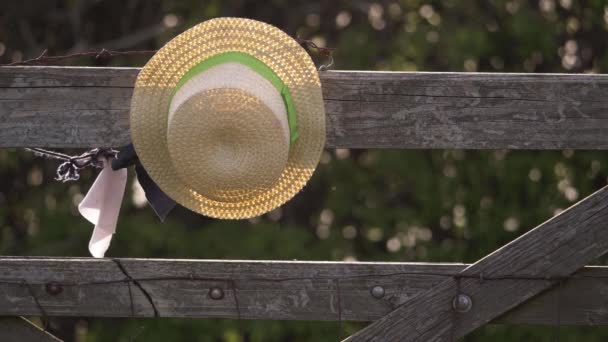 Straw hat hangs from a country wooden gate — Stock Video