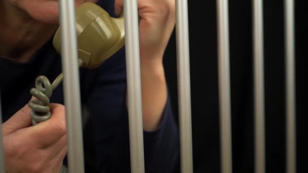 Prisonnier en cellule de prison faisant un appel téléphonique — Video