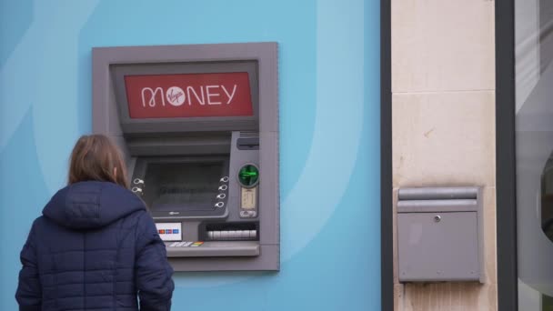 Vrouw met Virgin geld geldautomaat bij de bank in High Street — Stockvideo