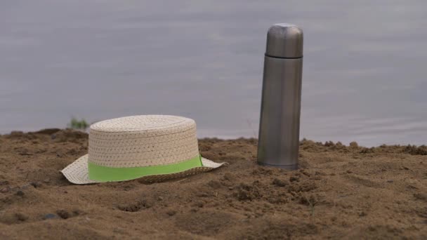 Strohhut und Fläschchen am Sandstrand — Stockvideo