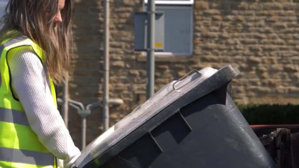 Kadın çöp toplayıcı, çöpü boşaltmak için ev çöplüğünü kullanıyor. — Stok video