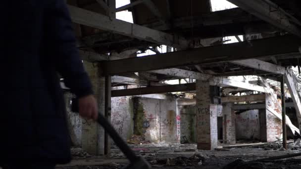 Преступник с топором преследует добычу в тени заброшенного здания — стоковое видео